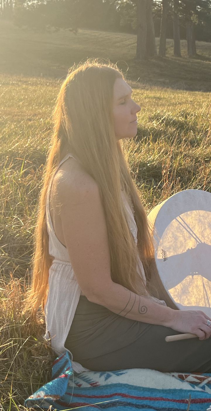 Destiny sitting in the meadow with her frame drum, eyes closed