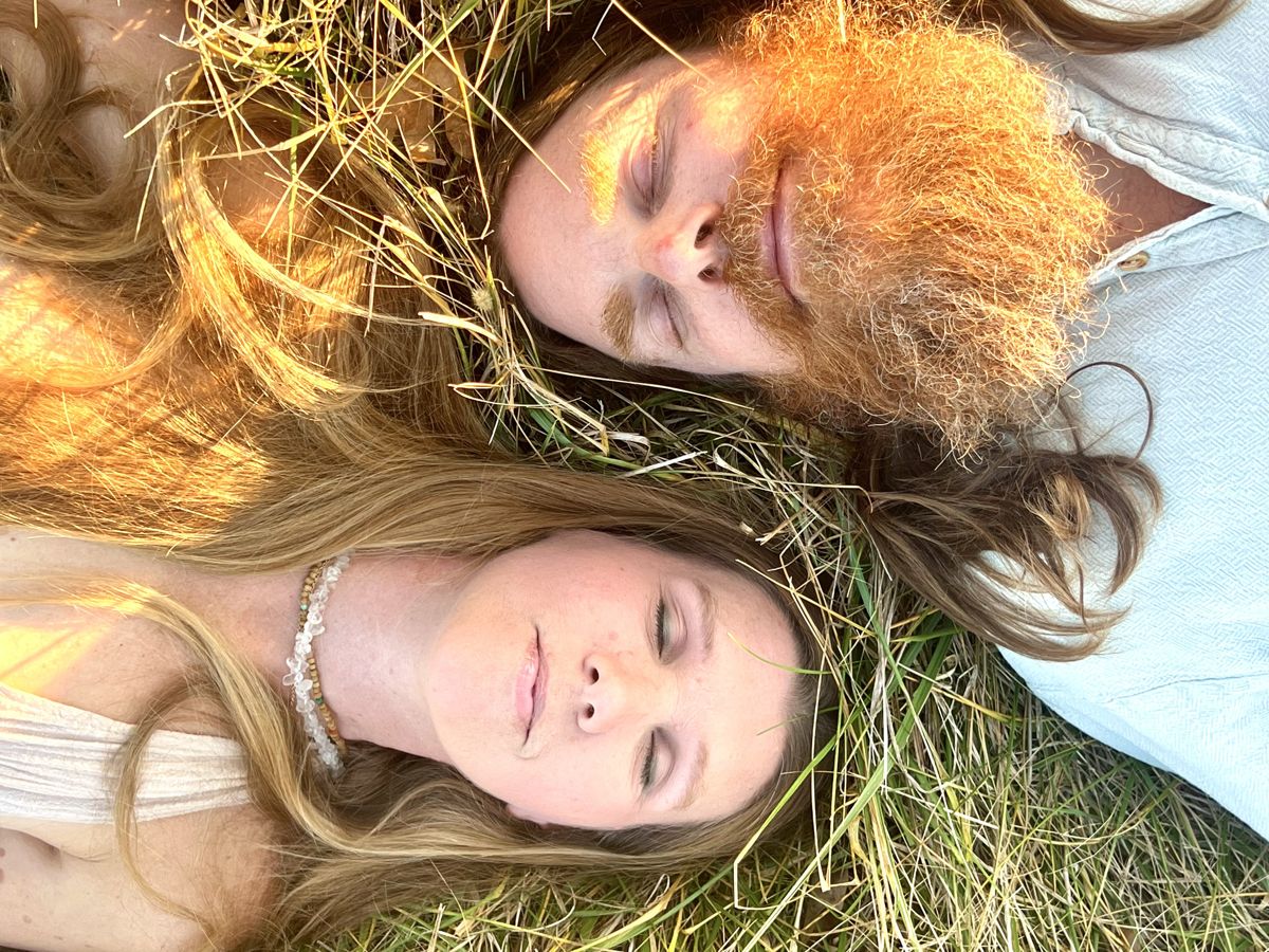 Destiny and Drew lying head to head in the grass, eyes closed